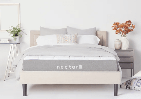 A Nectar mattress lays against a pale bedroom.