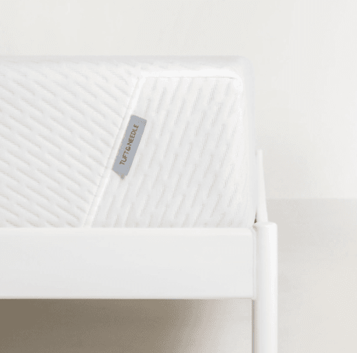 Original Tuft and Needle mattress; close-up of the bed's corner against a blank background.