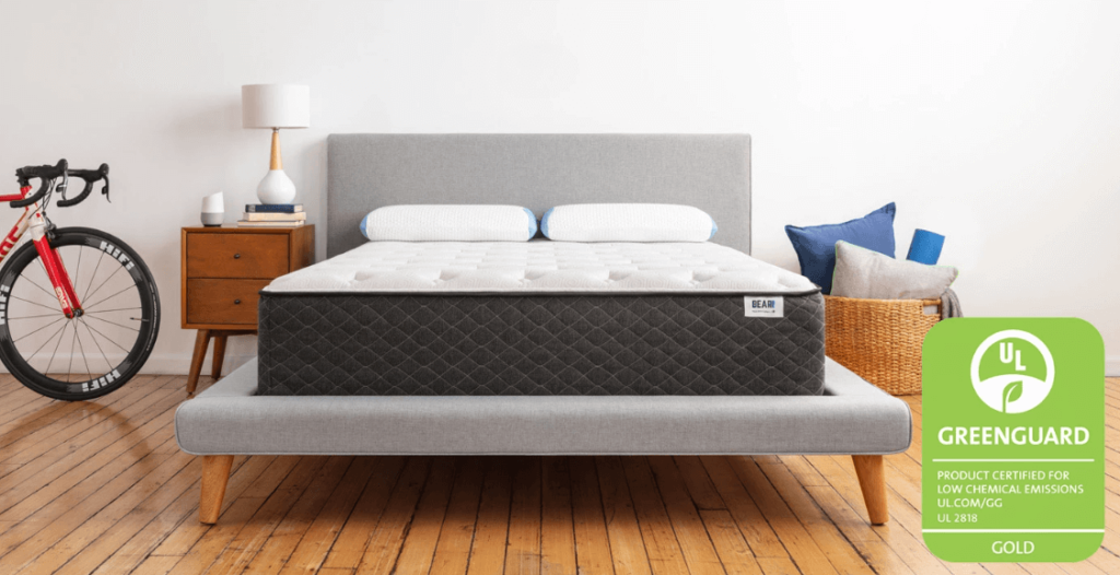 A gray and white Bear hybrid mattress on a gray bed frame.