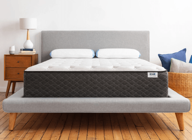 A white mattress with two white bed pillows sitting on a gray bed frame.