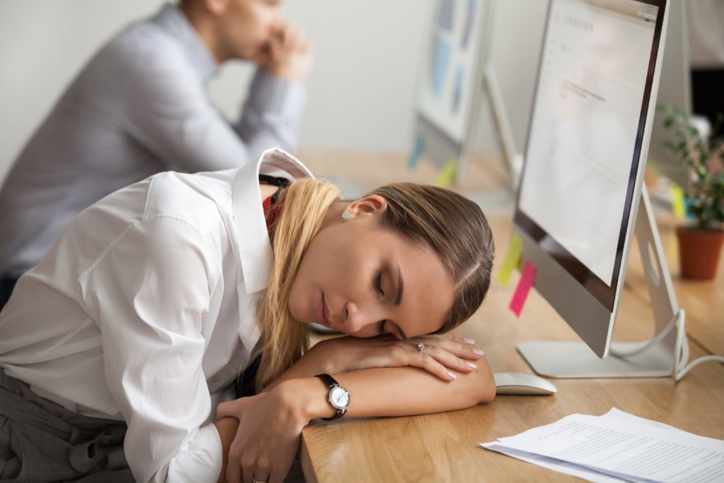 A woman with narcolepsy asleep on her desk in front of a computer.