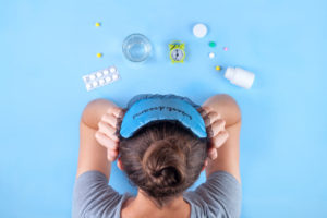 Insomnia concept. Sleep mask, a cure for insomnia, an alarm clock, a glass of water on a blue background. Depression and sleep concept.