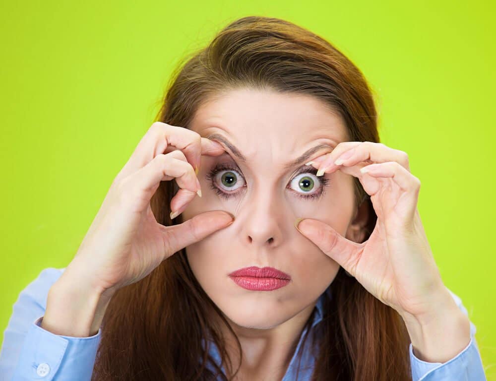 Closeup portrait sleepy, funny young woman, fingers keeping eyes open, low energy, trying to stay awake, focused, isolated green background. Negative facial expressions, emotions, feelings, reaction, sleep is for the weak concept.