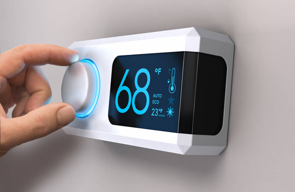 Hand turning a home thermostat knob to set temperature on energy saving mode. fahrenheit units. Composite image between a photography and a 3D background.