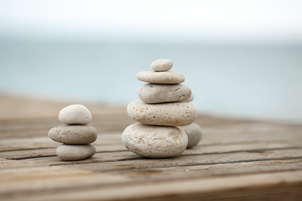 Stacks of meditation stones on a wooden dock.