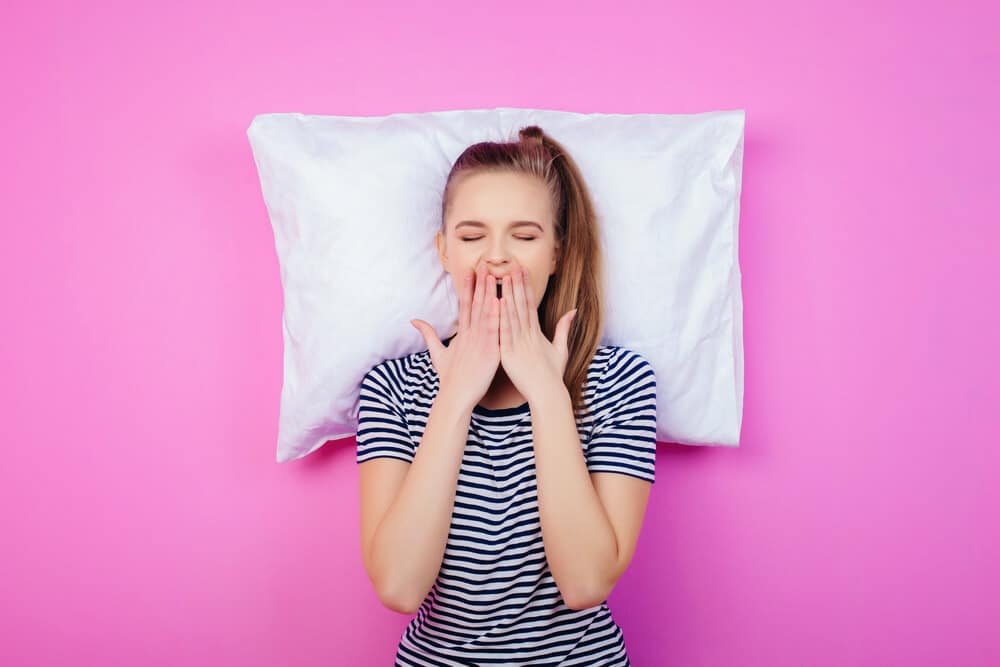 the young woman with a pillow on the pink wall; Dodow review concept.