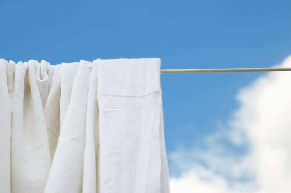 Dried washed bed sheets on rope in bright clear day