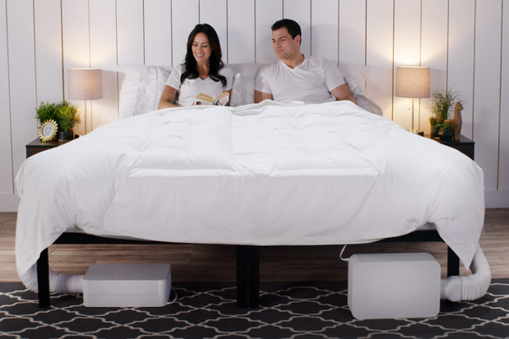 A man and woman on a white bed with two BedJets.