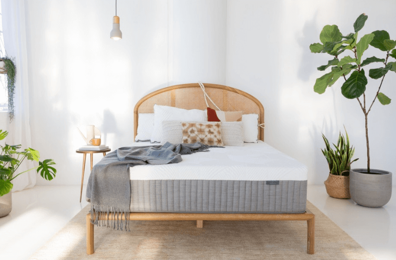 A Brentwood Home Cypress mattress rests on a bed frame in a neutral color room.