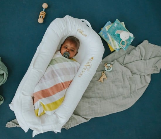 A baby rests in a personalized DockATot