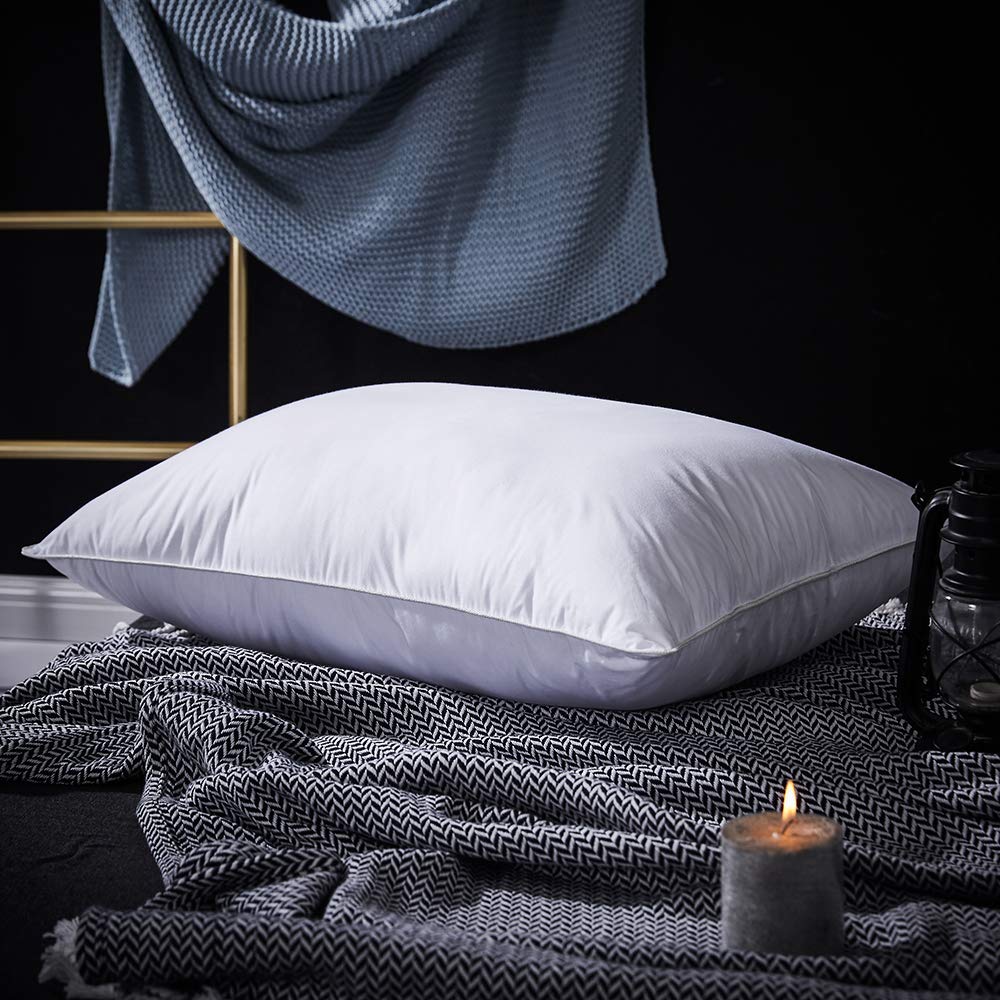 PALAWRAN down cushion with Egyptian cotton shell resting on dark bedsheets next to a lit candle.