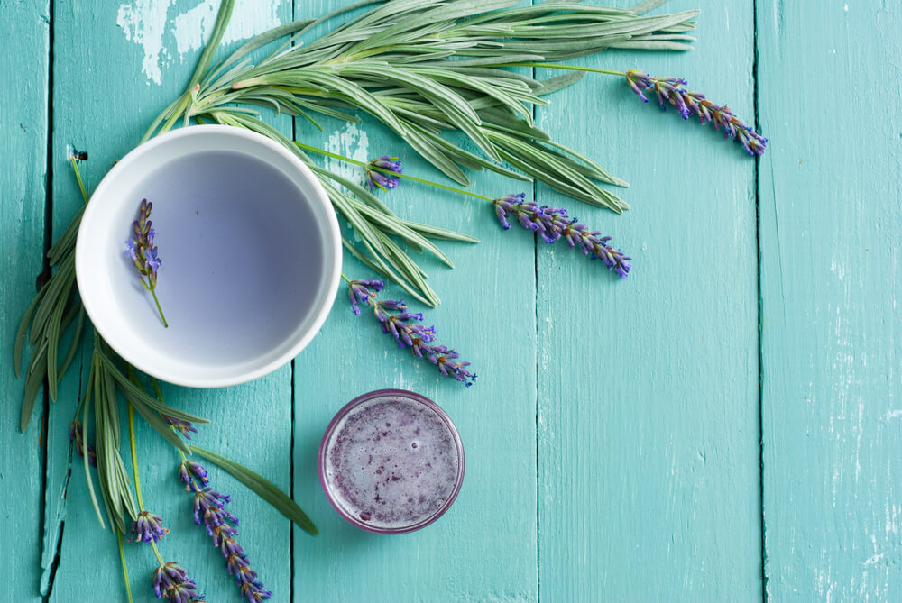 cup of lavender tea, flowers and syrup on blue wooden table background