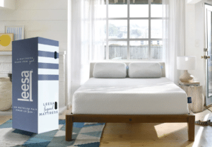 A white Leesa Legend hybrid mattress on a wooden bed frame with a blue and white box.