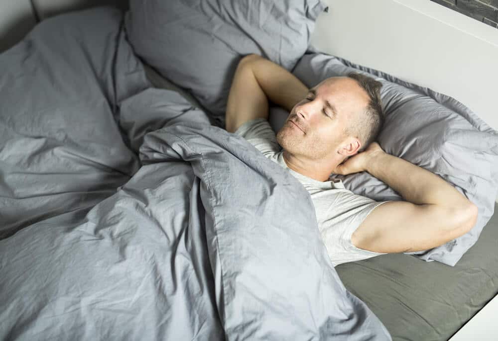 A Portrait of a young man from above sleeping in a bed.