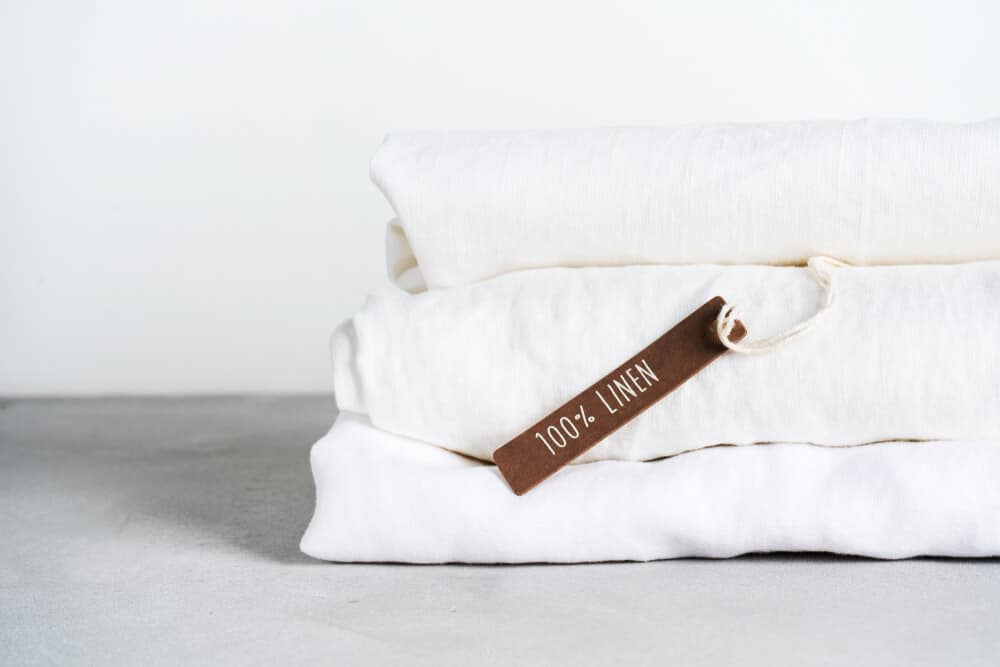 A white folded stack of flax linen sheets.