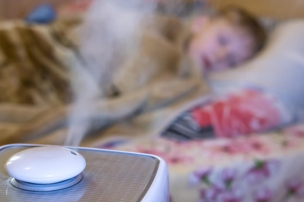 steam flow from a humidifier and an air ionizer in a blurred room with a sleep small child. Climatic device used to increase indoor humidity. humidifier for snoring concept