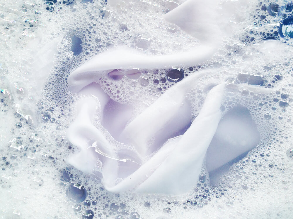 A white silk sheet soaks in soapy water.