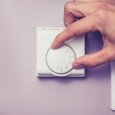 Hand turning dial on thermostat, best temperature for sleep concept.